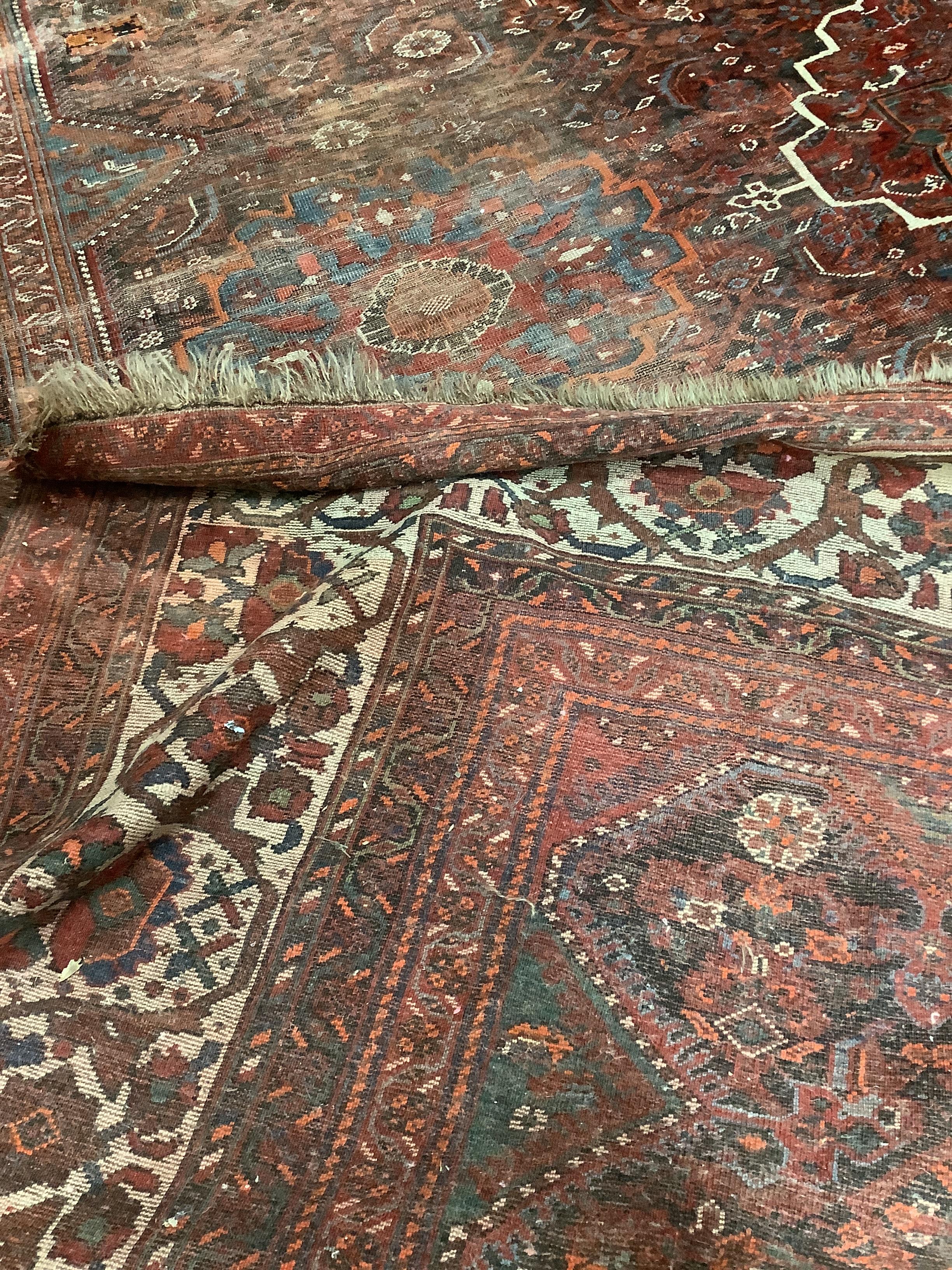 An early 20th century North West Persian red ground carpet, 410 x 348cm, worn and patch repaired.